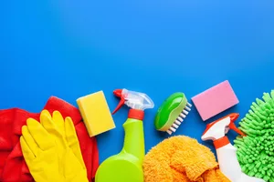 Germ hotspots in your home Cleaning sprays, sponges, dusters and rubber gloves lie on a blue background.