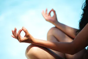 Naked yoga A woman sitting in a crossed-legged yoga pose against a blurred blue background