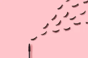 A mascara and eyelashes on a pink background A mascara and eyelashes on a pink background