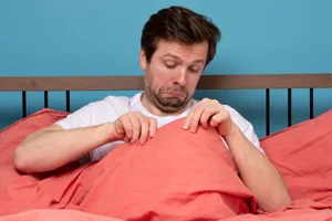 Facts about erections A worried man sits in bed and looks under the covers