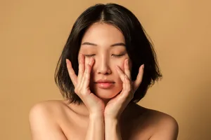 Ageing skin, hair and nails Woman caresses her face against a yellow background
