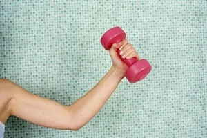 How to get rid of bingo wings A cropped shot of a woman lifting a dumbbell in front of a tiled wall