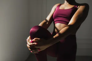 A woman wearing activewear doing a standing quad stretch A woman wearing activewear doing a standing quad stretch