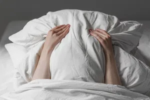 How to stop hangxiety A person covering their face with a pillow