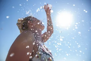 Heat stroke symptoms A woman pouring a bottle of water over herself