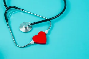 Unlock the secrets to a healthier heart A stethoscope with a heart-shaped object between the eartips is lying on a blue background.