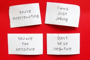 Gaslighting Examples of gaslighting on four pieces of paper, against a red background
