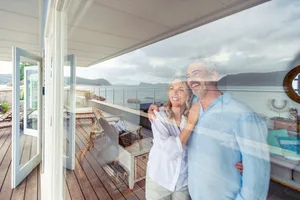 UK pension A retired couple looking out at the sea through a floor-to-ceiling glass window