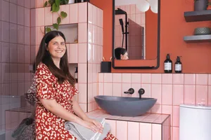 Riannon Selcuk home Riannon Selcuk sits in her contemporary bathroom which features blush pink metro tiles and black hardware