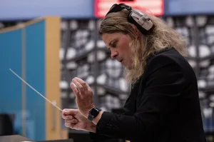 Nathan Henninger recording Romanza Nathan Henninger, a white man with shoulder-length blond hair conducts in a recording studio with headphones on