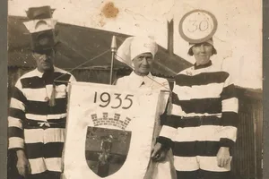 Header image Black and white photograph of a man in a black and white striped outfit with a set of traffic lights on his head, an older woman in a nurse's costume and a woman in a black-and-white striped outfit with a 30 speed sign on her head