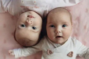 Babies twins lying on a pink blanket looking up Two babies popular baby names 2025