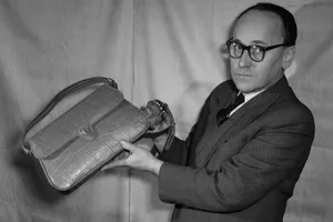 Mode Accessoires DDR Black and white photograph of a man wearing glasses holding a leather handbag