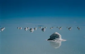 Salar de Uyuni, Salt flats, Bolivia Saltbergs formed in crystalised mounds on a completely flat almost dried up lake floor, the surface and land a continuous blue colour, the salt bergs reflected in the surface water.