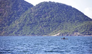 Solitary fisherman rowing canoe, Lake Malawi, Malawi, Africa. Lake Malawi