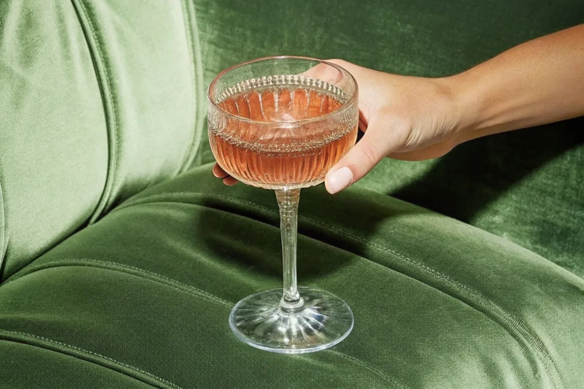 best-mocktail-recipes-valentines-day-2025 Woman holding cocktail glass in front of sofa