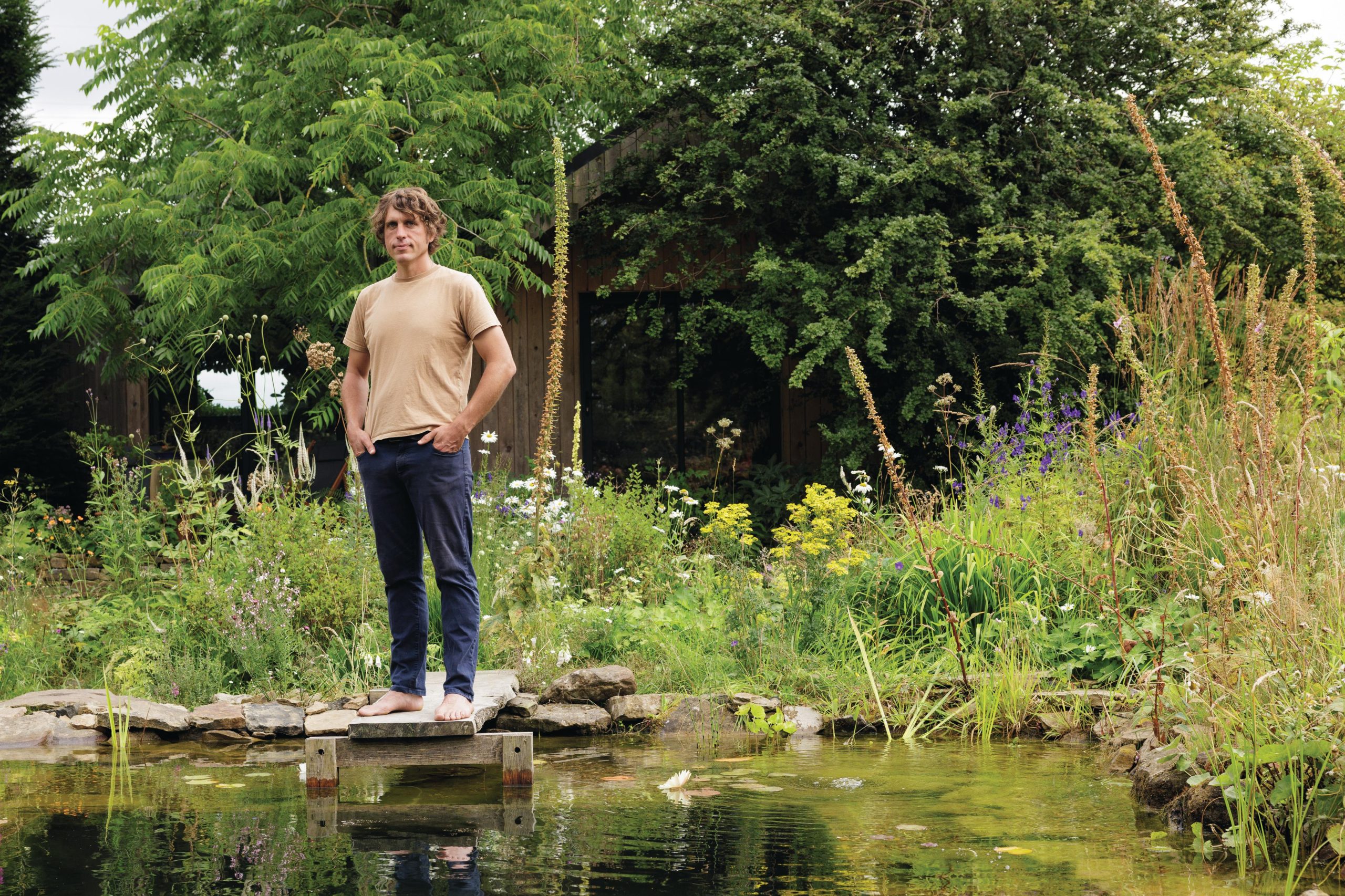 Man stood in garden by swimming pond