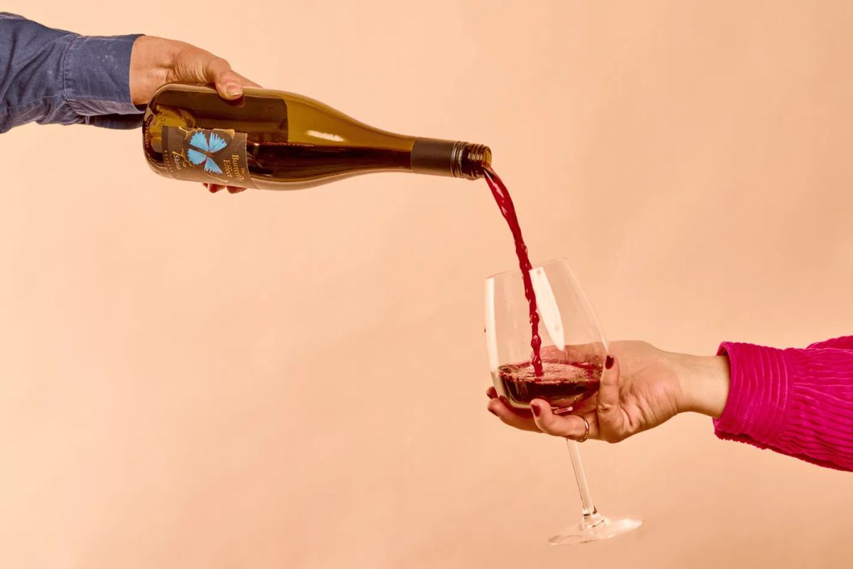 A hand pours wine into a glass.
