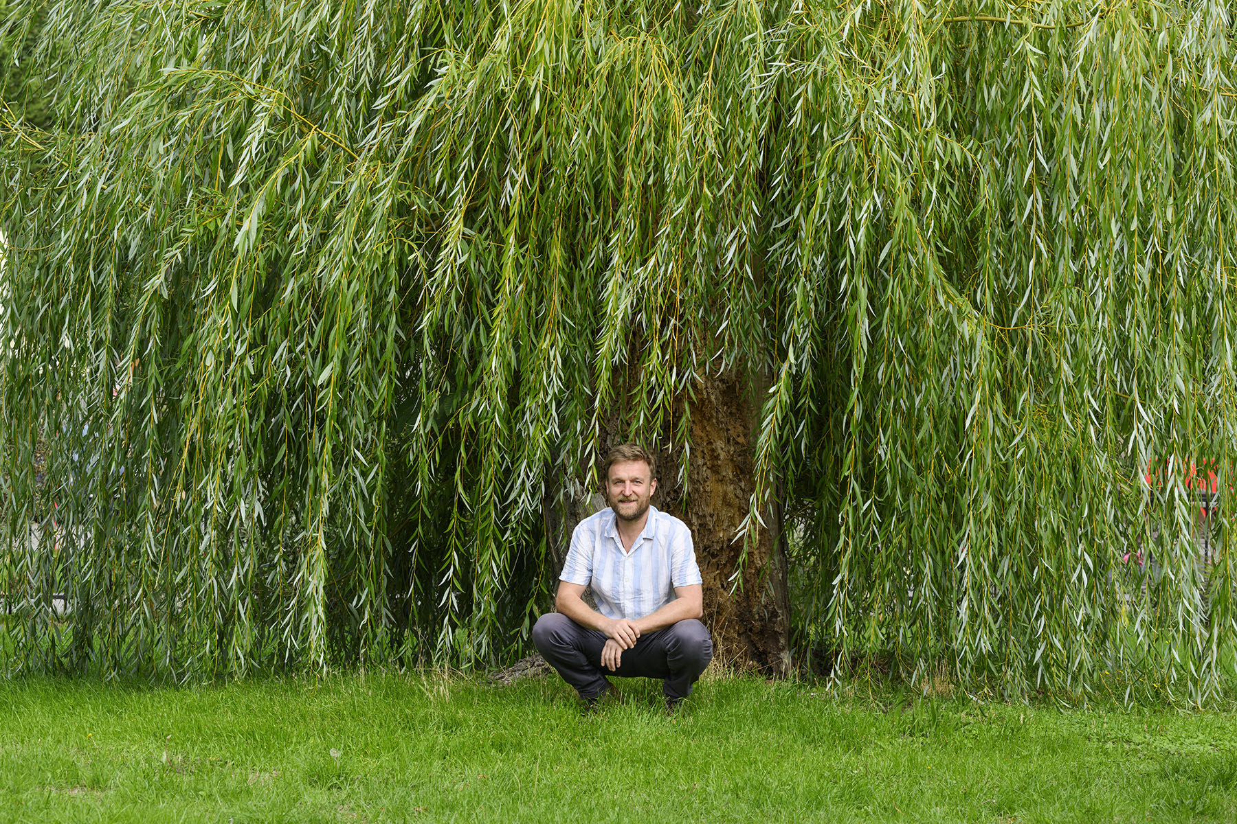 Man crouching in front of a tree