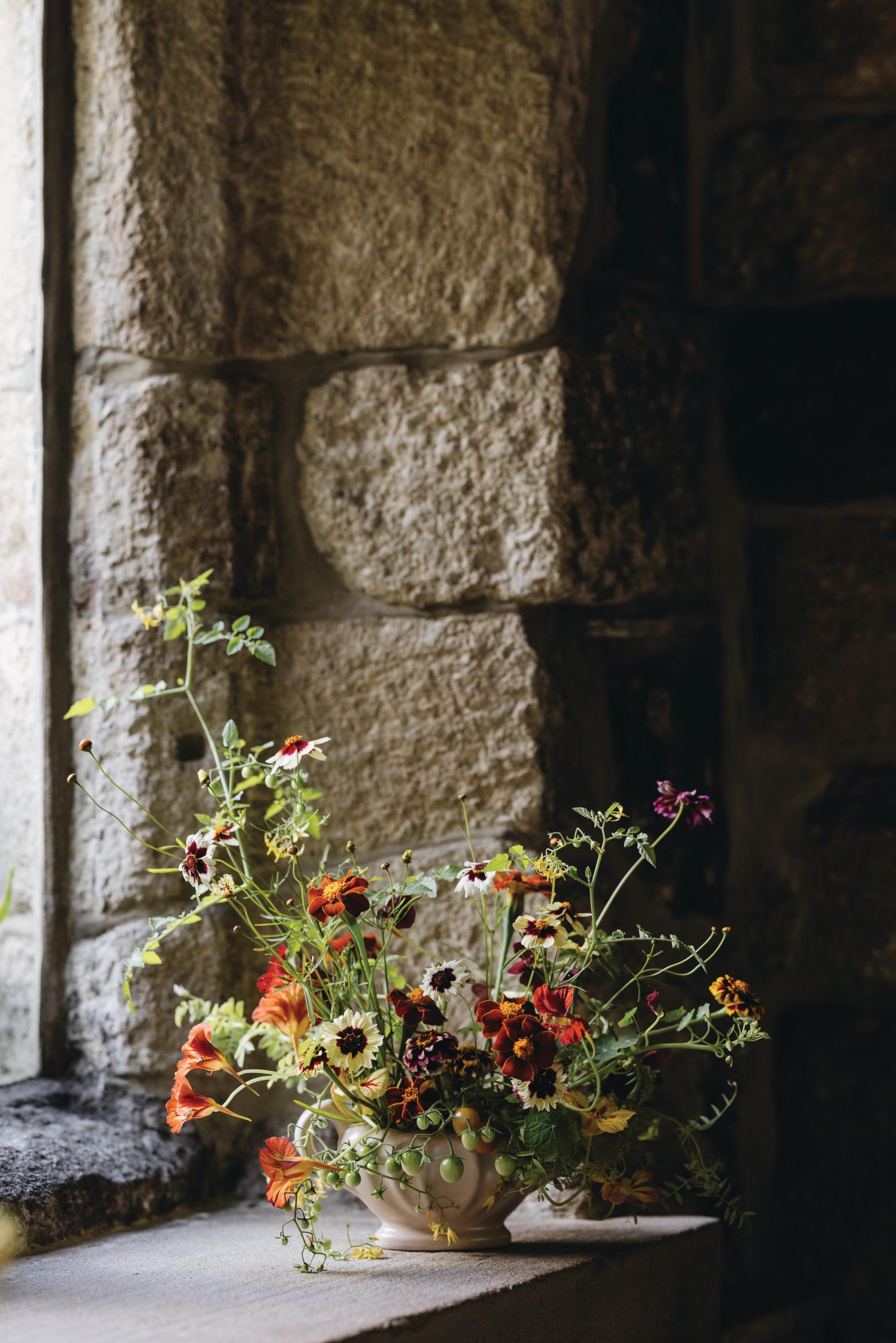 Flowers arranged in vessel by window
